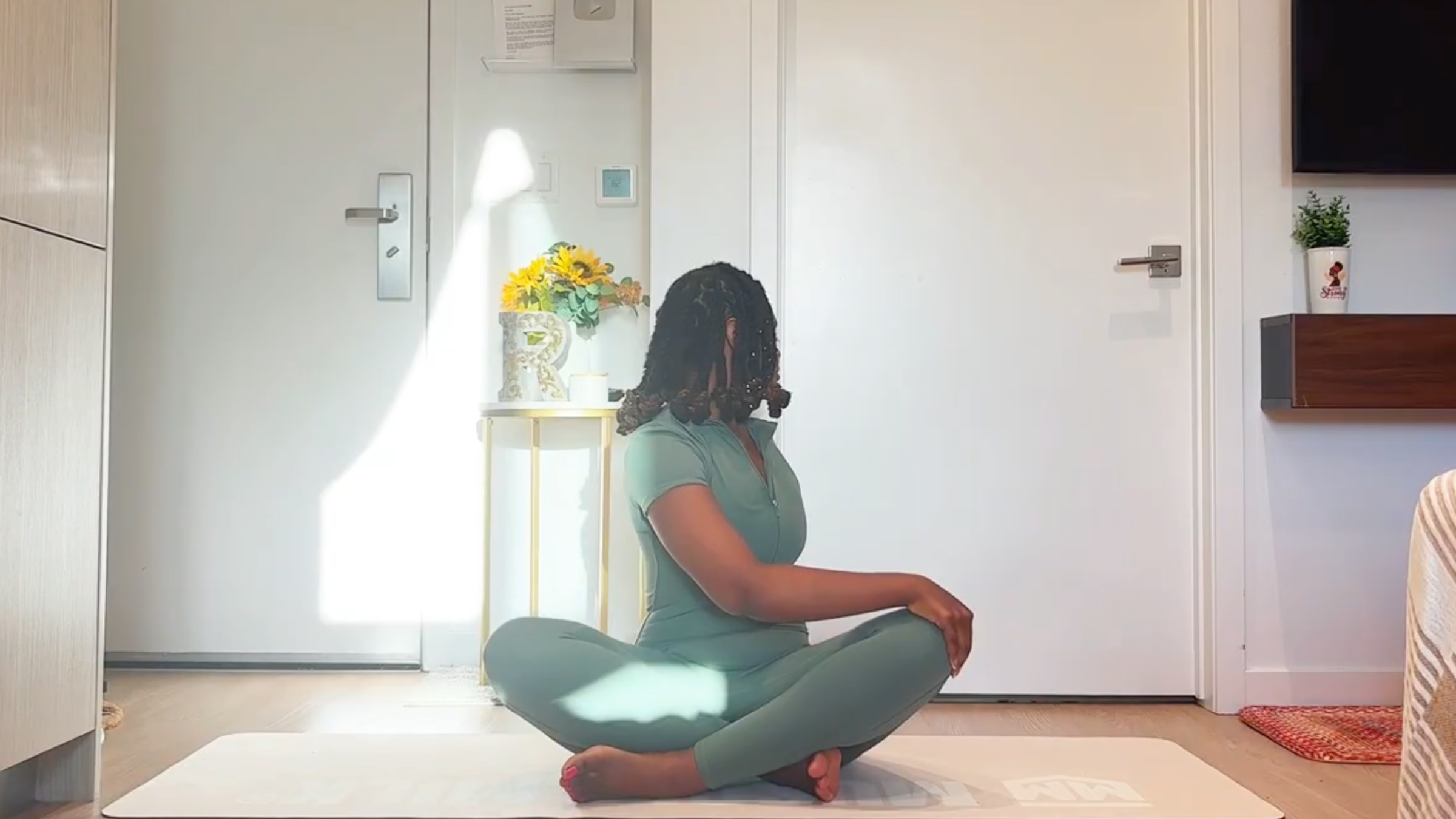 Ramoni Overton sitting tall on a yoga mat, twisting upper body to the side with one hand placed on the opposite knee.